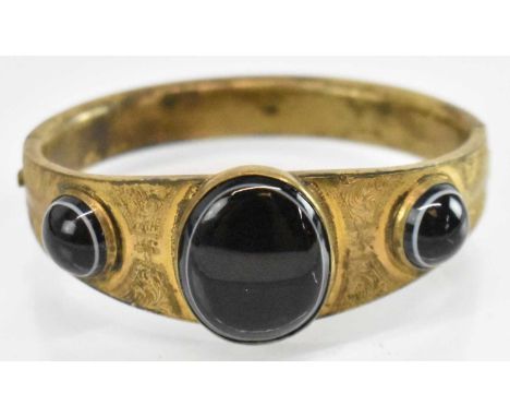 A pinchbeck bangle set with three black hardstones, diameter 6.5cm.