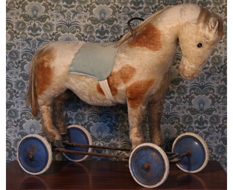 A large straw-filled cream and brown mohair ride-on or push along Horse on wheels, felt saddle, pull chord to neck, mounted o