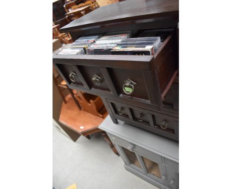 A modern mahogany effect set of three CD drawers, in a medieval style, containing eclectic mix of compact discs