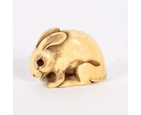 A Japanese ivory netsuke, 18th/19th Century, in the form of a crouching hare, with amber inlaid eyes, 4cm long/Provenance: Sp