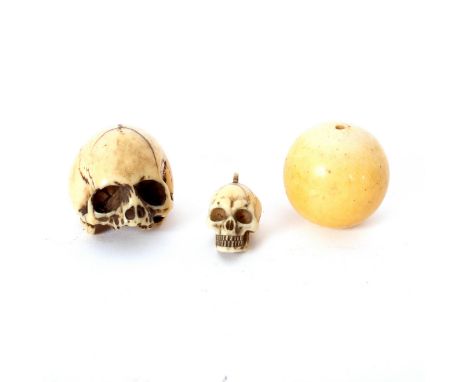 A Japanese ivory netsuke, 19th century, in the form of a skull, 4cm long, another carved ivory skull and an ivory ball (3)/Pr