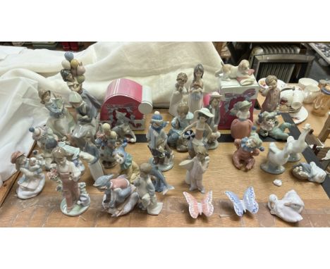 A collection of Lladro and Nao porcelain figures including a balloon girl, clown, children, butterflies, puppy, kitten etc 