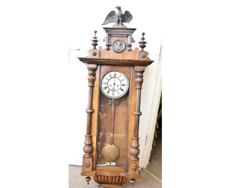 A Vienna walnut regulator clock, two weight example with enamel face, Roman numerals, and ornate pediment, surmounted with an