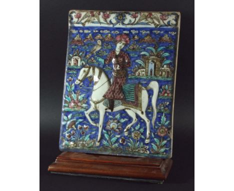 PERSIAN TILE, Qajar style, cast in relief with a man on horse back going hunting with a hawk, buildings, flowers and mountain