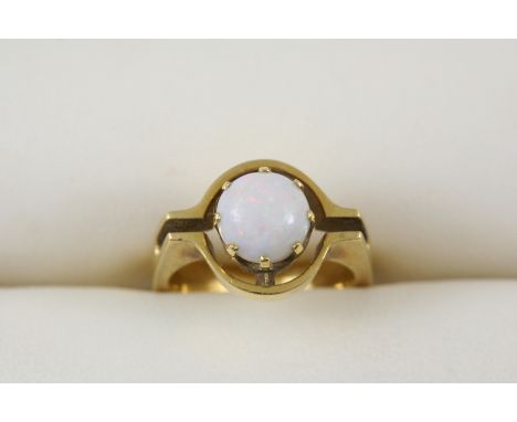 AN OPAL SINGLE STONE RING the circular cabochon opal is set in 18ct. gold. Size L.