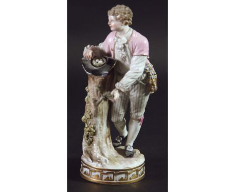 MEISSEN FIGURE, late 19th century, model 122, of a young man standing by a tree trunk with a nest of eggs in a hat, blue cros