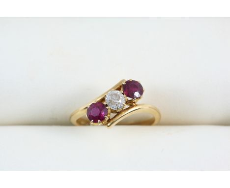 A RUBY AND DIAMOND THREE STONE RING the old brilliant-cut diamond is set with two circular-cut rubies, in 18ct. gold. Size M.