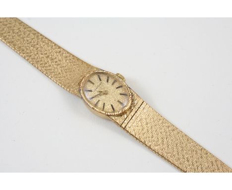 A LADY'S 9CT. GOLD WRISTWATCH BY LONGINES the signed oval-shaped dial with baton numerals, on an integrated gold bracelet, wi
