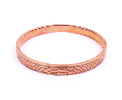 A late Victorian 9ct rose gold bangle. Engine turned pattern throughout. Hallmarked gold 9ct, London. 78mm diameter, 8.3mm wi