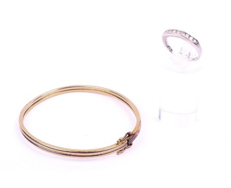 A white gold diamond set ring and a yellow metal bangle. The ring having nine round brilliant cut diamonds of 0.25 carats sta