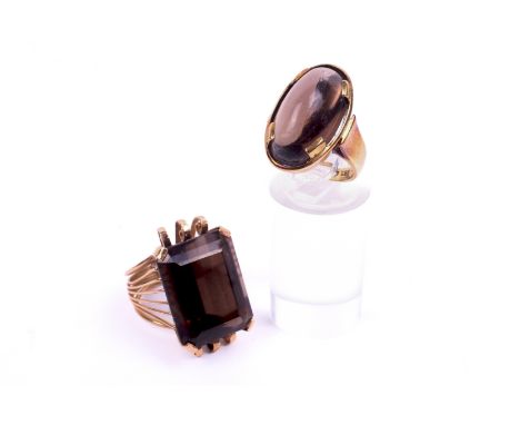 Two stone set yellow metal rings. Each set with semi precious material assessed as brown quartz. Tested as minimum 9ct yellow