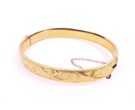 A yellow metal hinged bangle. Having engraved decoration to the exterior, marked '9ct' to the interior, clasp is broken, 10.0