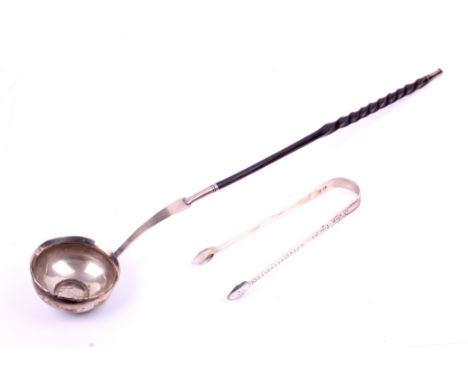 A white metal toddy ladle and a pair of Georgian sugar tongs. The ladle constructed of a Spanish 1778 Carolus III silver coin