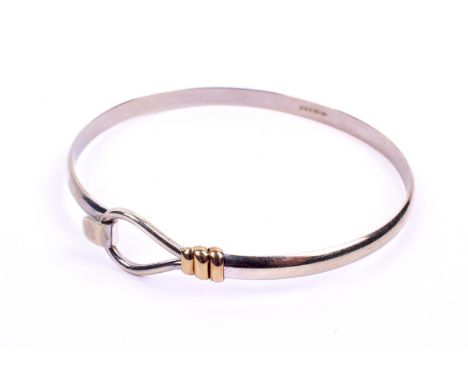 A hallmarked 9ct white gold bangle. With tension clip fitting and yellow gold details. 60mm diameter approximately. 10.5g gro
