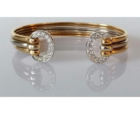 A gold bi-colour cuff bangle with diamond decoration, stamped and tests for 18ct, 23.6g