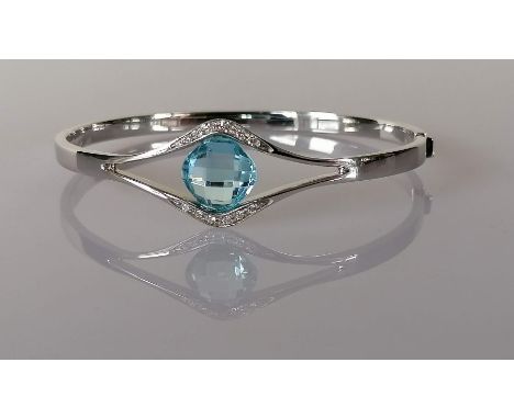 A white gold bangle with split shank enclosing a blue topaz, 12.80 carats, and diamond decoration, Cyprus assay marks for 18c