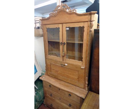 A 3' 3" continental pitch pine secretaire chest with pierced pediment, flanking applied decoration, pair of glazed panel door