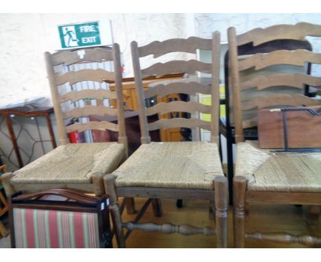 A set of six polished oak framed ladder back dining chairs with woven rush seats, set on turned supports