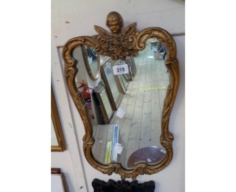 A vintage ornate gilt framed mirror with cherub pediment and shaped plate