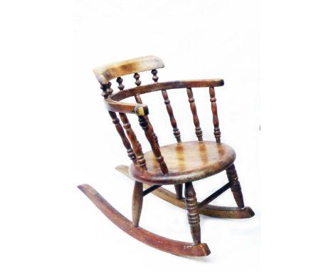 A 19th Century stained beech child's bow spindle back rocking chair with circular seat panel and ring turned supports