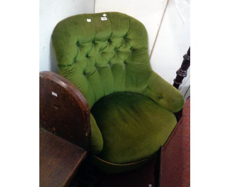 A late Victorian boudoir tub chair upholstered in green button back velour, set on turned front legs with porcelain castors