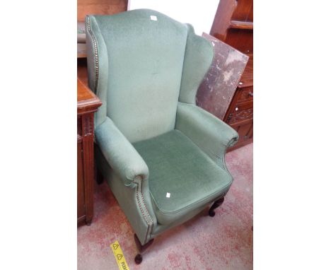 A modern wing back armchair in the antique style with studded jade green velour upholstery, set on cabriole front legs with p