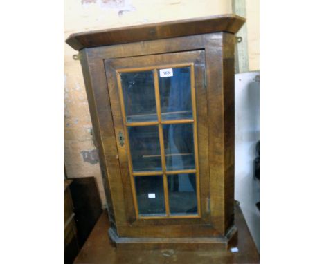 A 22" antique mahogany and mixed wood wall hanging corner cabinet with beaded glazed panel door and canted sides