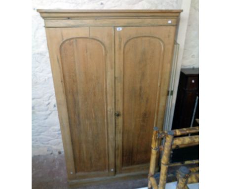 A 4' 1" Victorian stripped pine double wardrobe with moulded cornice and pair of arched panel doors enclosing linen slides, s