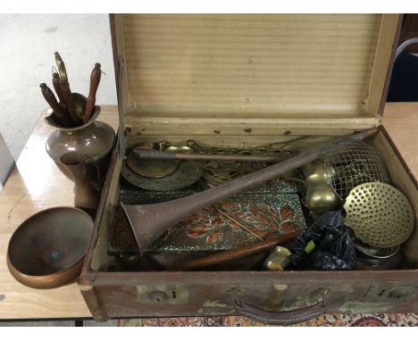 A vintage travel case containing brass and copper ware items.