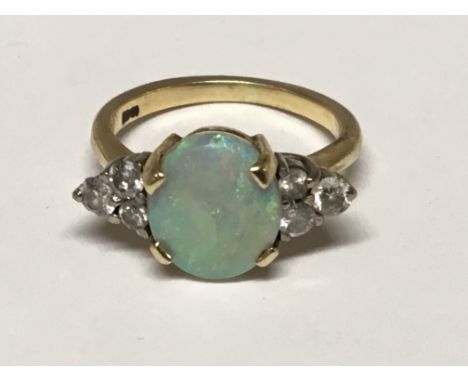 An opal and diamond ring the vibrant oval opal flanked by six brilliant cut diamonds, set in yellow gold ring size Q.