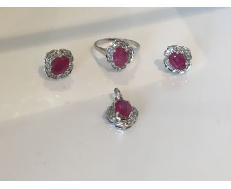 A 9ct white gold ruby and diamond ring with matching earrings and pendant