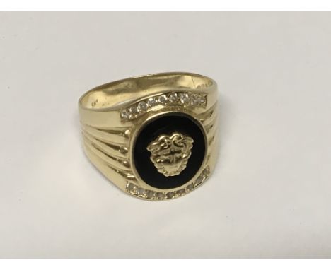 A Gents 14ct Yellow Gold ring set with black onyx with a classical raised mask, with two single rows of diamonds. Ring size Y