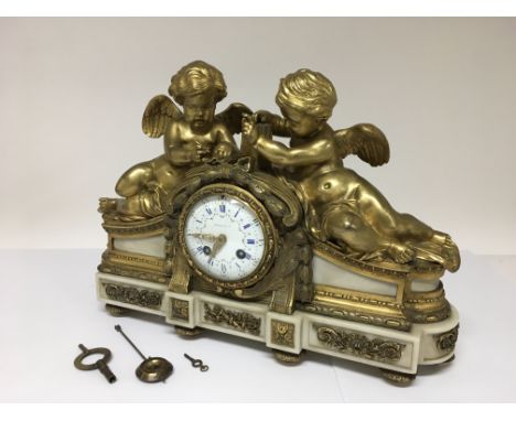 A French ormalu 8 day mantle clock by Tiffany & Co surmounted by two cherubs, the enamel clock face decorated with floral swa