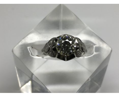 A good size diamond ring, the central diamond of pale yellow colour set in platinum, measuring 1.52 carat, flanked by further