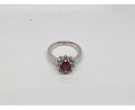 A 18 carat white gold ladies ring set with a good coloured ruby flanked by brilliant cut diamonds in the form of a flower hea