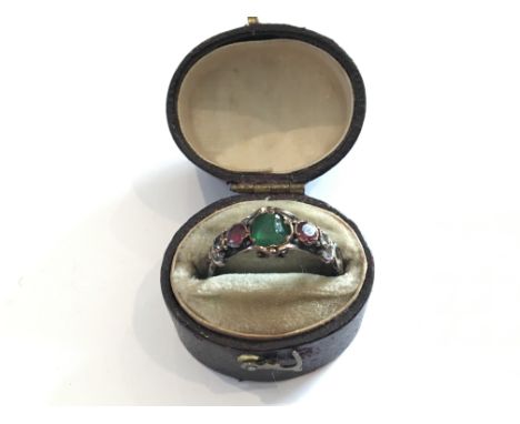 An Antique ring set with an Emerald flanked by Rubys. Unmarked Gold.In a oval ring box.