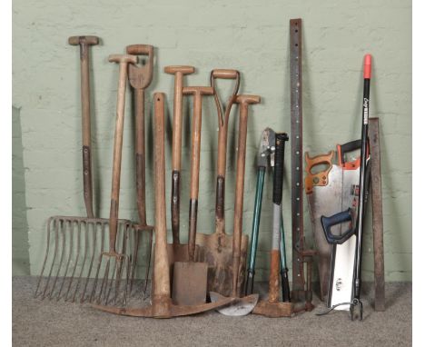 A collection of assorted tools to include spades, rakes, pickaxe, sledgehammer, saws, etc.  