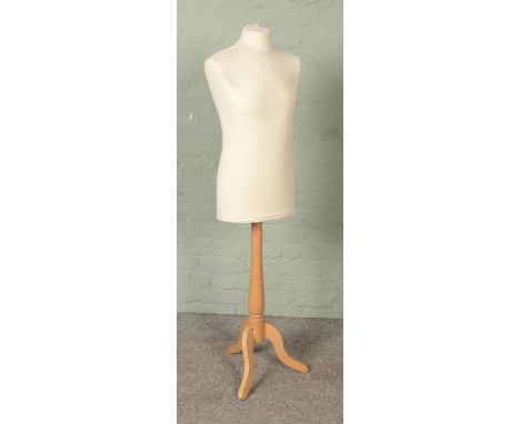 A modern polystyrene dress form mannequin raised on turned wooden stand.  