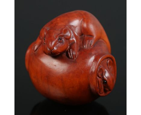 A hand carved hardwood netsuke of a mouse on a vase  