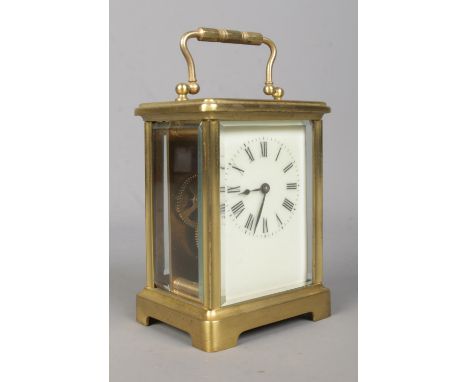 A brass carriage clock, with beveled glass panels, open top escapement and swing handle. Featuring Roman Numeral dial and Fre