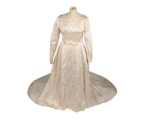 A 1962 Jean Varon Wedding Dress, in cream silk with long sleeves and shaped cuffs, scooped neck, bow to the waist, pleated lo