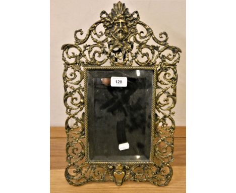 A cast brass easel mirror, with mask and scroll pierced border, 44cm. 