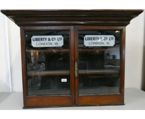 A mahogany glazed two shelf cabinet, with Liberty &amp; Co., London applied decal, 67 x 88 x 26 cm. 