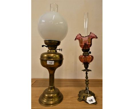 A brass oil lamp, with white glass shade, 60 cm, together with a cranberry glass oil lamp, 57 cm (2). 