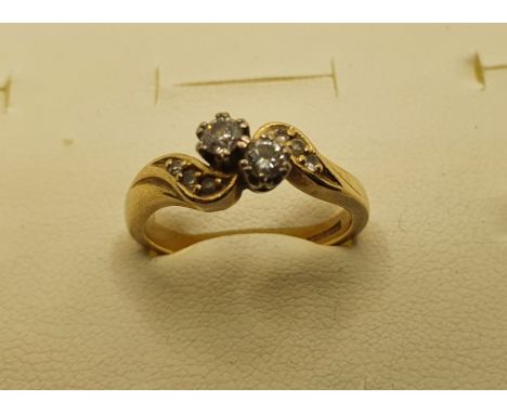 An 18ct gold two stone diamond cross over ring, set with brilliants, diamond set shoulders, 3.5 gms, size K 1/2. 