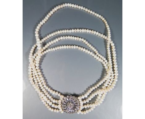 A Four Strand Pearl Necklace with Diamond brooch clasp in a precious white metal setting, the central stone c. .5 ct