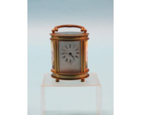A miniature oval carriage clock, enamelled dial and timepiece movement, brass case inset with two ceramic plaques, each paint