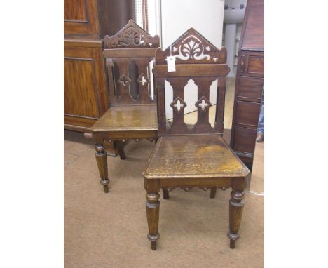 A pair of Victorian oak hall chairs, pierced architectural backs and solid seats, octagonal tapering legs 