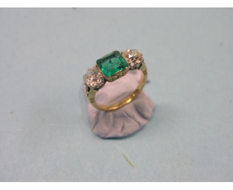 A yellow metal diamond and emerald ring, two brilliant-cut diamonds, each approx. 0.75ct., claw settings, central step-cut em