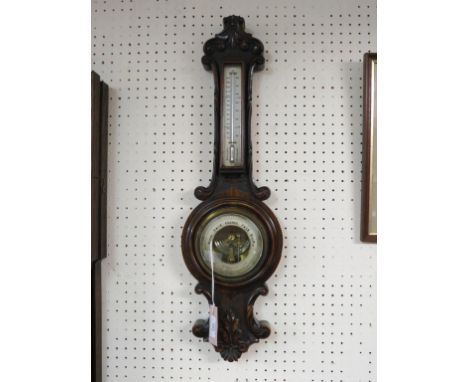 A Victorian walnut aneroid wheel barometer, dial signed T. Buss, Hatton Garden, case carved with leaf-scrolls, 26in.